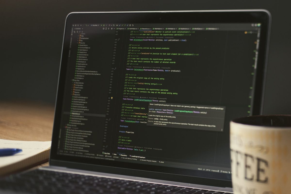 Laptop memaparkan kod dengan secawan kopi di sebelah - membina website dengan AI